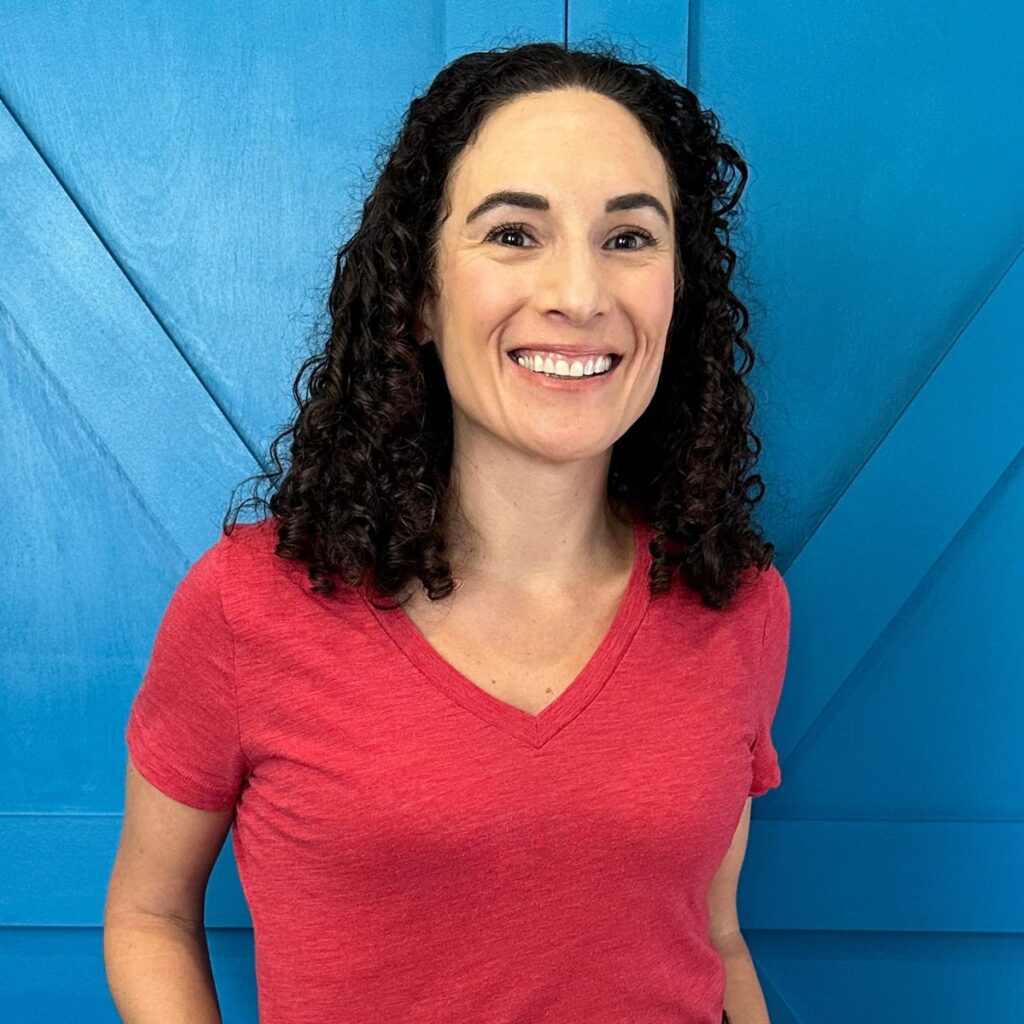 Laura Fuentes in a red shirt standing in front of a blue door